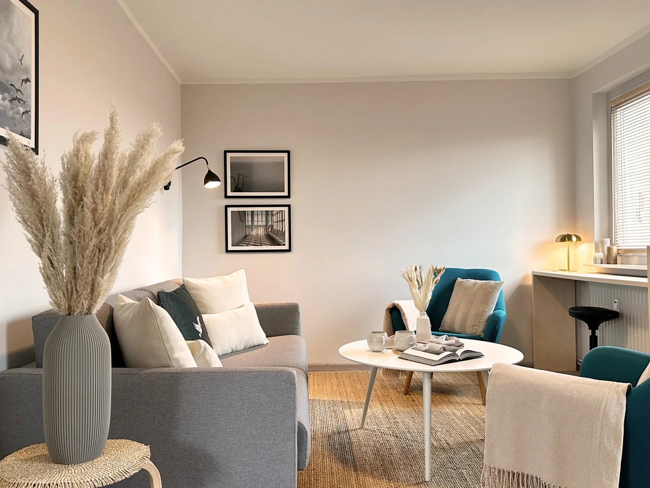 Wohnbereich von MAGONI+ Apartment No. 1 mit petrolfarbenen Sesseln und grauem Sofa